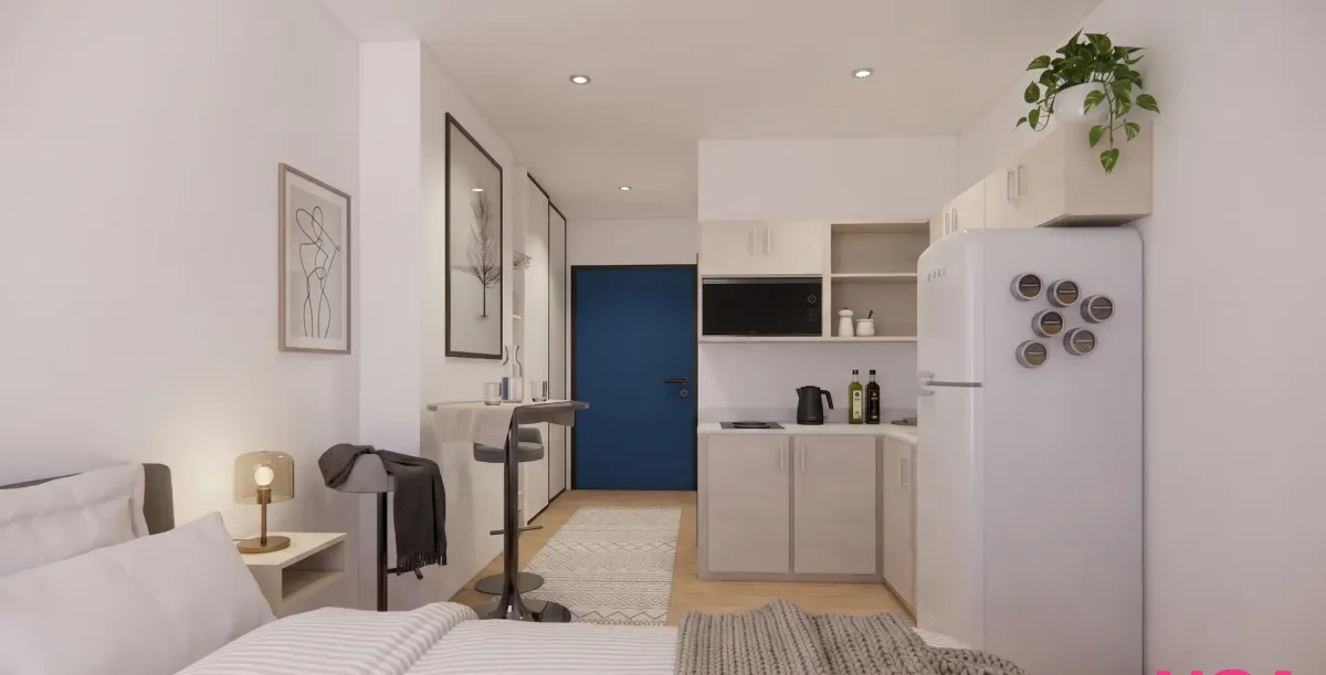 A renovated studio suite at The Horton with a bed, kitchenette, and entry door